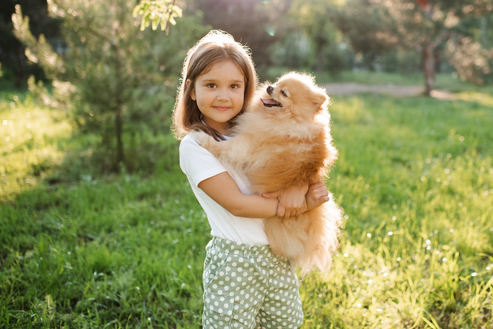 a little girl holding a little dog