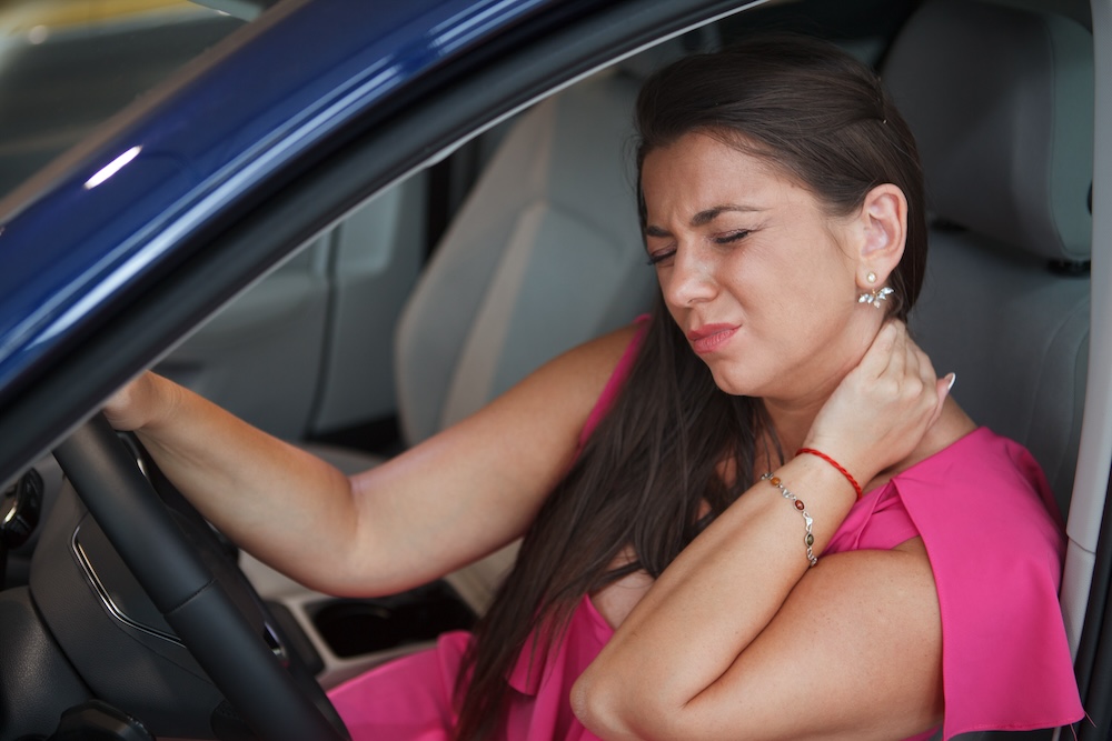a woman having neck pain while driving