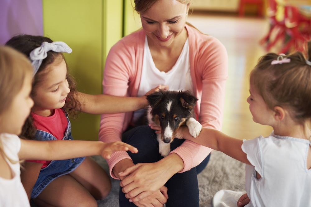 kids petting a dog on their teachers lap